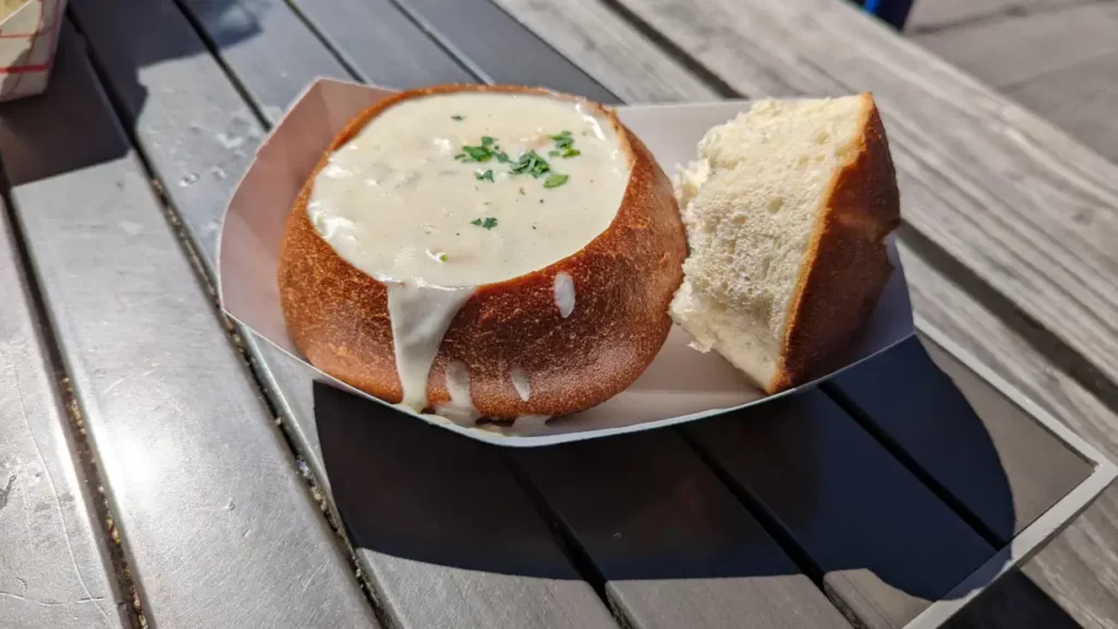 Gros plan sur un Clam Chowder : une soupe crémeuse et dégoulinante de palourdes servie dans une miche de pain.