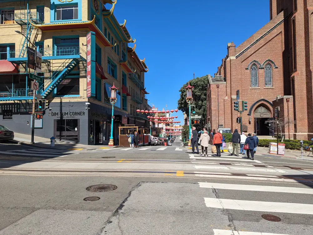 Des touristes sont en train de visiter Chinatown à San Francisco et se dirigent vers Grant Avenue, bordée par Old St Mary’s.