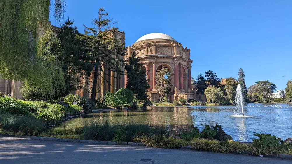 Bâtiment du Palace of Fine Arts, entouré par les eaux et caché par les feuillages.