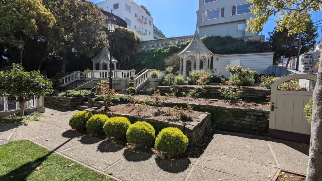 Fay Park vu de l’intérieur et ensoleillé. On y voit deux belvédères en bois blanc grillagé ainsi que ses jardins en terrasse.