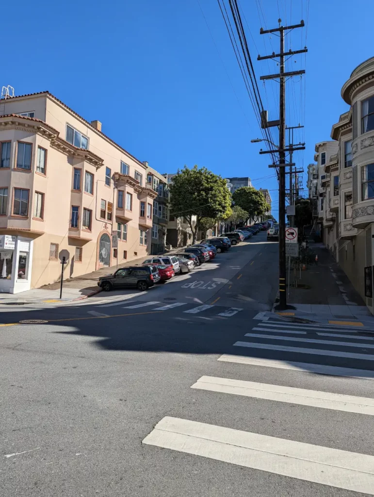 Rue montante et verdoyante de Filbert Street, au croisement de Polk Street. Des maisons victoriennes se trouvent à droite et à gauche.