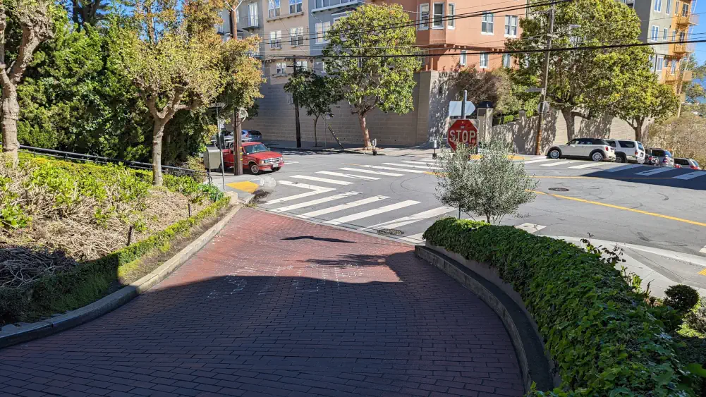 Fin de la portion sinueuse de la Rue Lombard, menant sur un stop et le croisement avec Leavenworth Street, sur laquelle circulent des voitures.