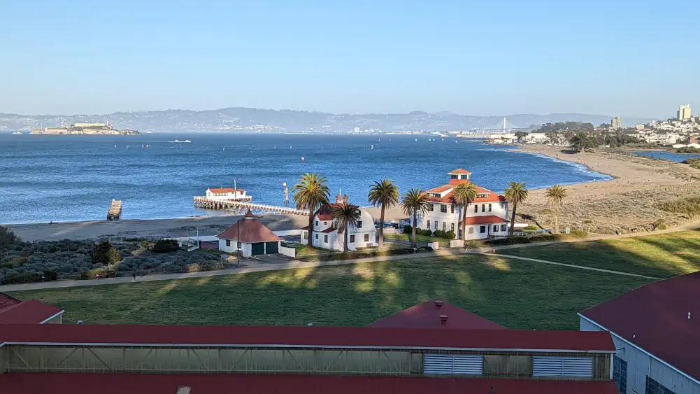 Vue en plongée sur la plage de “Golden Gate Beach”, sur laquelle se trouvent 3 maisons blanches avec un toit rouge.