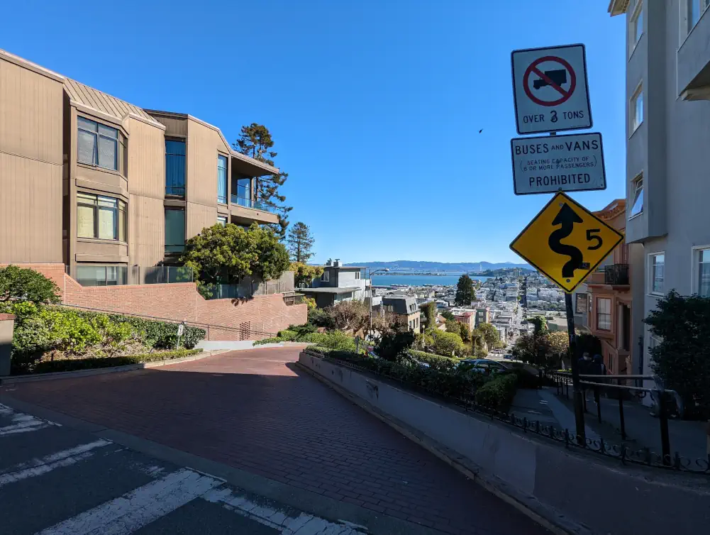 Sommet de Lombard Street au croisement de Hyde Street, qui offre un aperçu de la baie de San Francisco. A droite se trouve un panneau de signalisation.