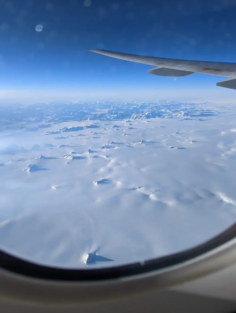 Vue en vol sur une immense étendue de neige composée de plaines et pics montagneux, offerte en allant visiter San Francisco.