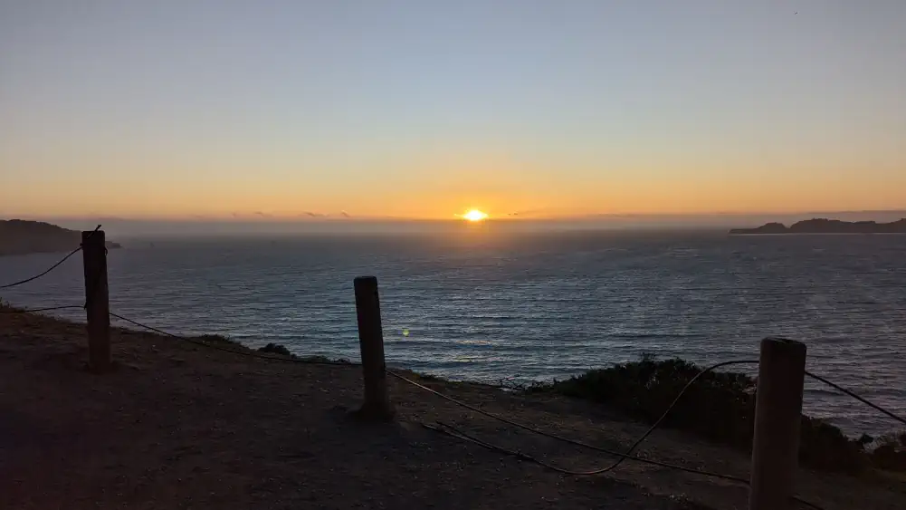 Point de vue situé à côté du pont de San Francisco. Le soleil disparaît de l’horizon et passe sous le niveau de l’océan.