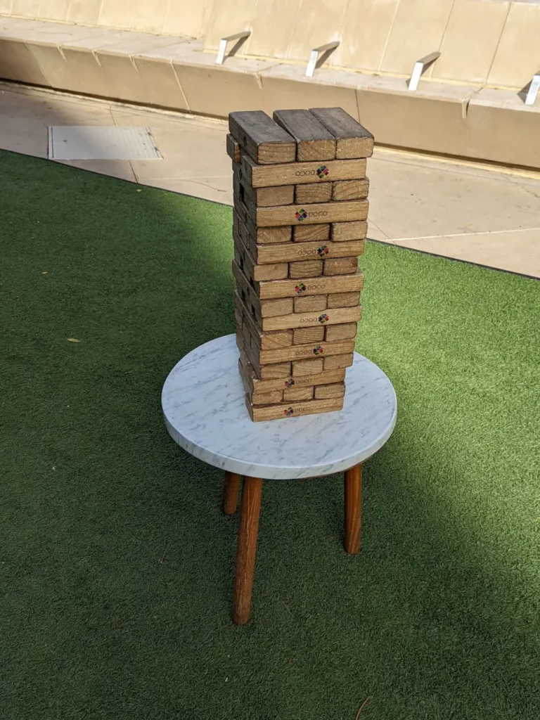 Petite table scandinave sur laquelle se trouve une tour géante en bois de Jenga.