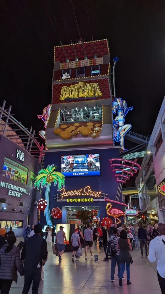 Arrière de l’édifice Fremont Street Experience. Il est éclairé par plein de panneaux lumineux, tels qu’un cocotier et des danseuses de cabaret. Au sommet se trouvent des câbles de tyrolienne.