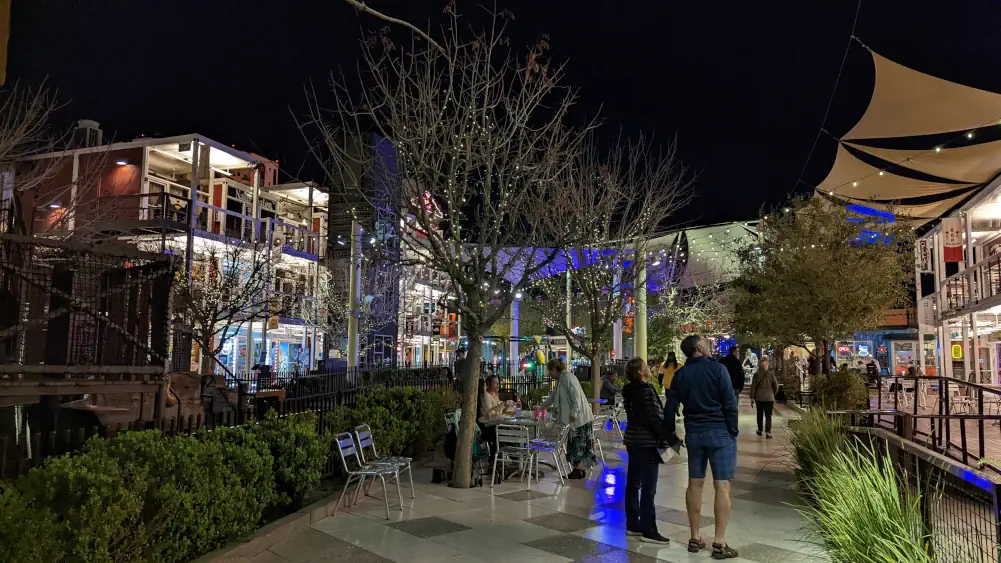 Cour intérieure du Downtown Container Park, encerclée par des conteneurs. Elle est traversée par des arbres et des visiteurs, et éclairée par des ampoules façon guinguette.