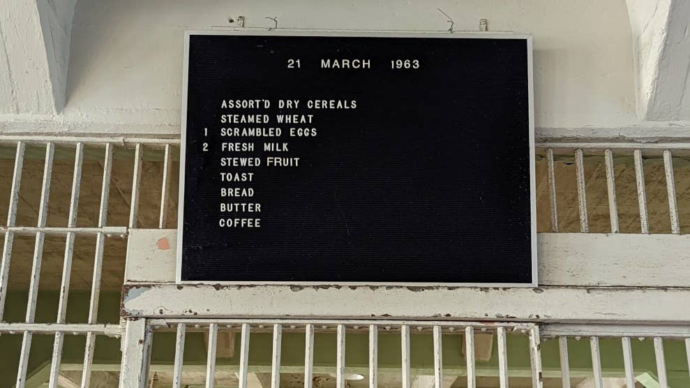 Panneau noir sur lequel est inscrit le menu d’un petit-déjeuner. Au-dessus de la liste est inscrite la date “21 march 1963”.