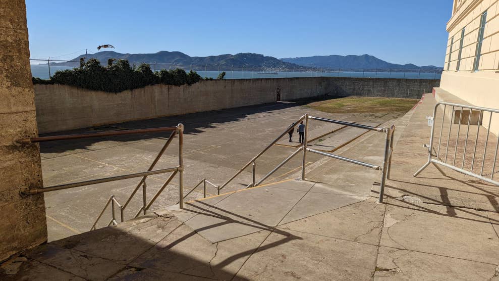 Vue sur l’immense cour des prisonniers, du haut de ses escaliers. Elle est vide. Au loin se trouvent les reliefs de la baie de San Francisco.