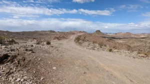 Route de terre déserte et rocailleuse survolée d’un ciel bleu, typique d’un road trip sur la cote ouest des USA.
