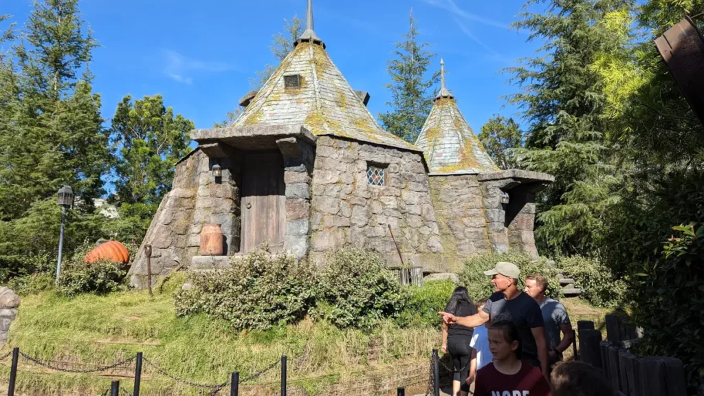 Cabane en briques d’Hagrid, entourée d’herbe, d’outils de jardinage et d’une citrouille. Le toit comporte de la moisissure.