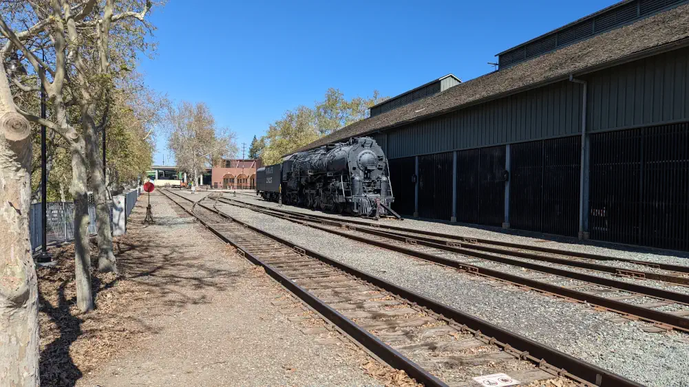 Voie ferrée au bout de laquelle se trouve une vieille locomotive noire “Santa Fe 2925”.