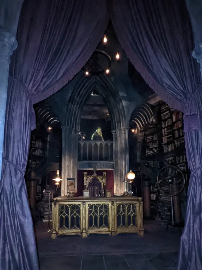 Bureau de Dumbledore, caché derrière deux grands rideaux violets. On aperçoit son hologramme au-dessus de son bureau.