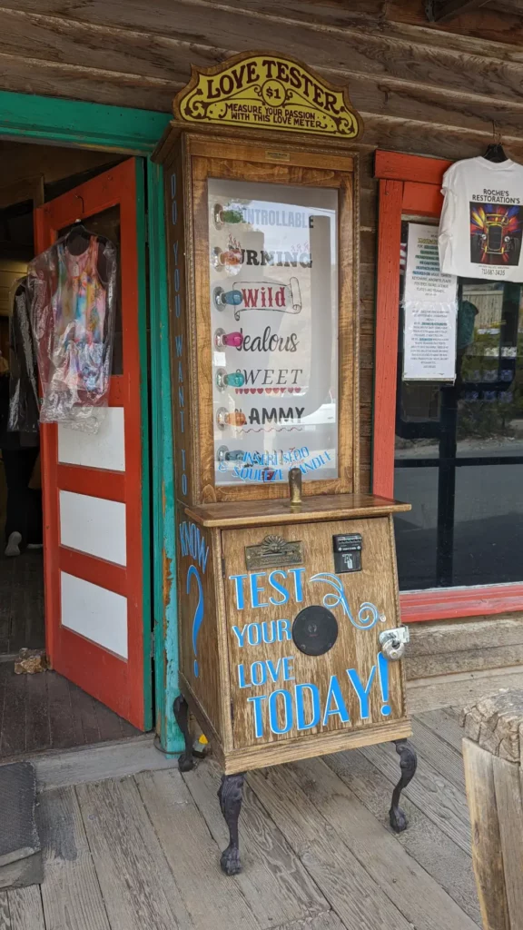 Haute machine en bois avec pieds en métal “Love tester”, devant une boutique d’Oatman.