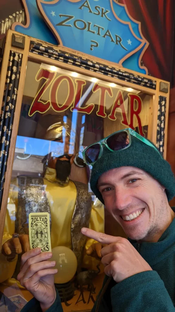 Zoom sur Nano devant la machine diseuse de bonne aventure Zoltar Speaks, heureux d’avoir reçu son ticket jaune.