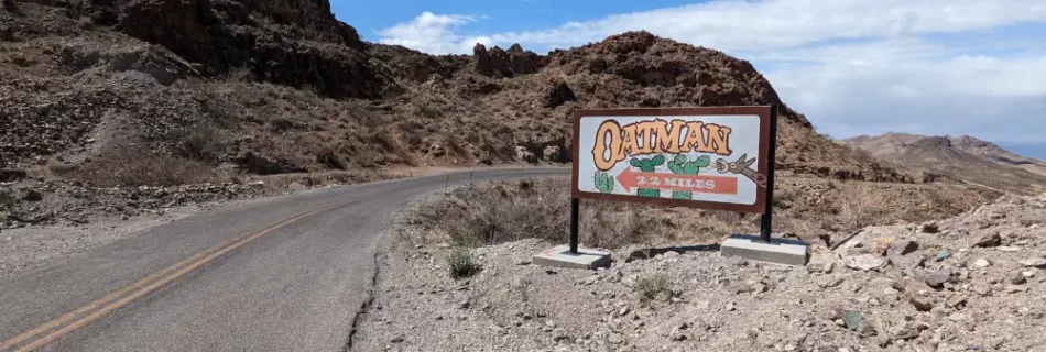 Panneau indiquant Oatman à 3,5 kilomètres. Il est situé sur le bord de la Route 66, en plein désert rocheux.