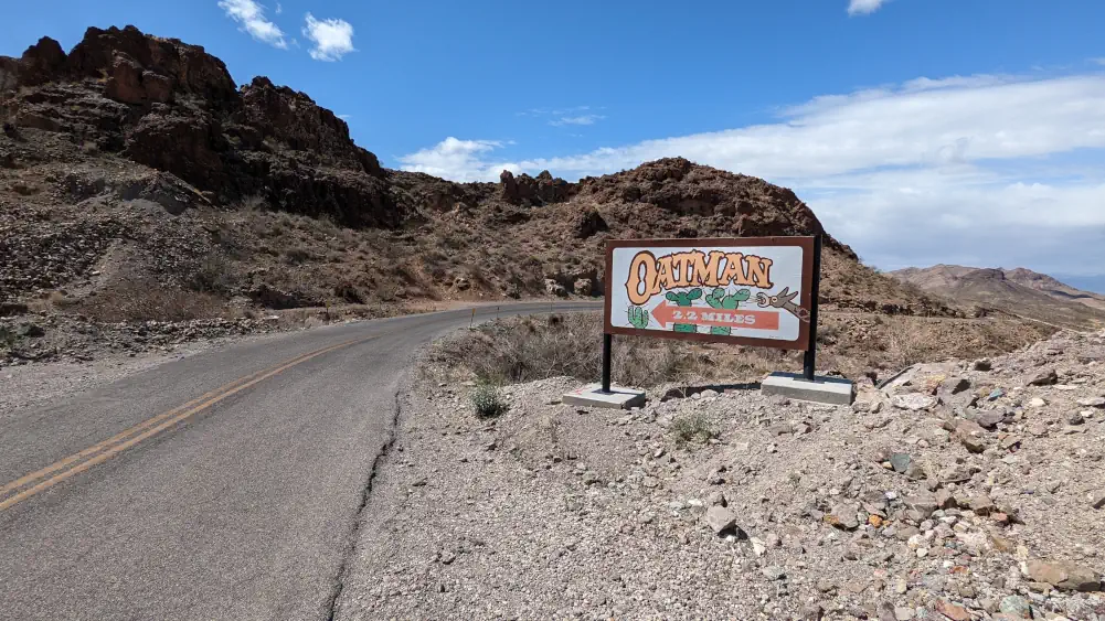 Panneau indiquant Oatman à 3,5 kilomètres. Il est situé sur le bord de la Route 66, en plein désert rocheux.