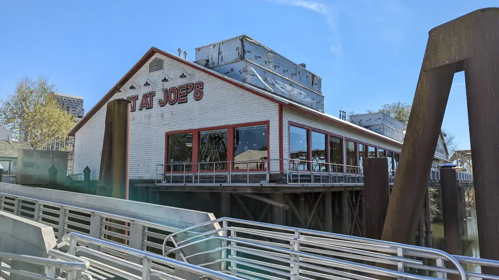 Façade blanche du restaurant “Joe's Crab Shack”. Ses fenêtres aux bordures rouges s’ouvrent sur le fleuve du Sacramento.