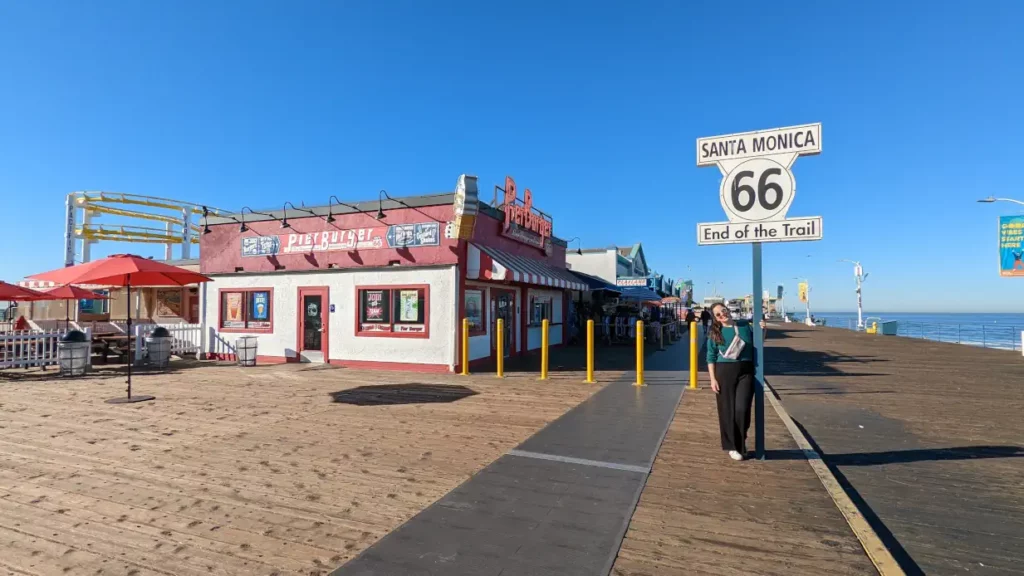 Aperçu de la jetée de Santa Monica à Los Angeles. Hélo se tient debout à côté du panneau marquant la fin de la Route 66.