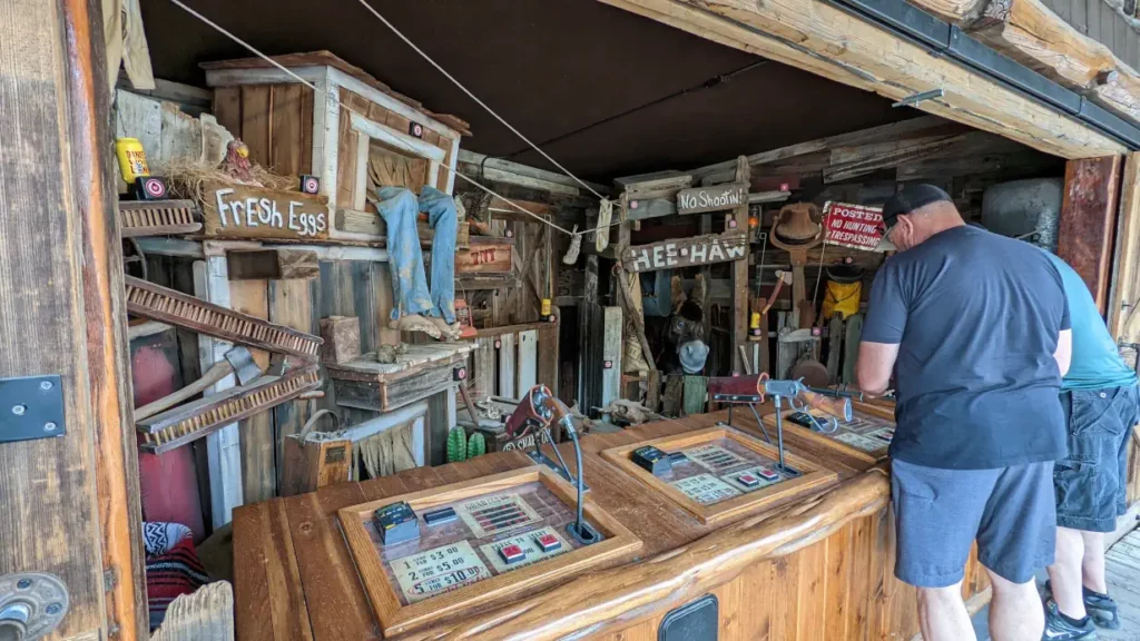 Deux hommes sont en train de se préparer sur le stand de tir à Oatman. Deux jambes et une tête d’âne sortent du décor.