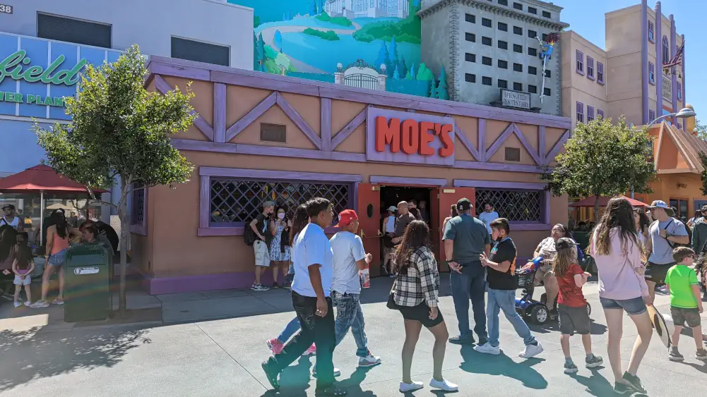 Façade principale de la taverne de Moe, devant laquelle circulent des visiteurs du parc Universal Studio à Los Angeles.