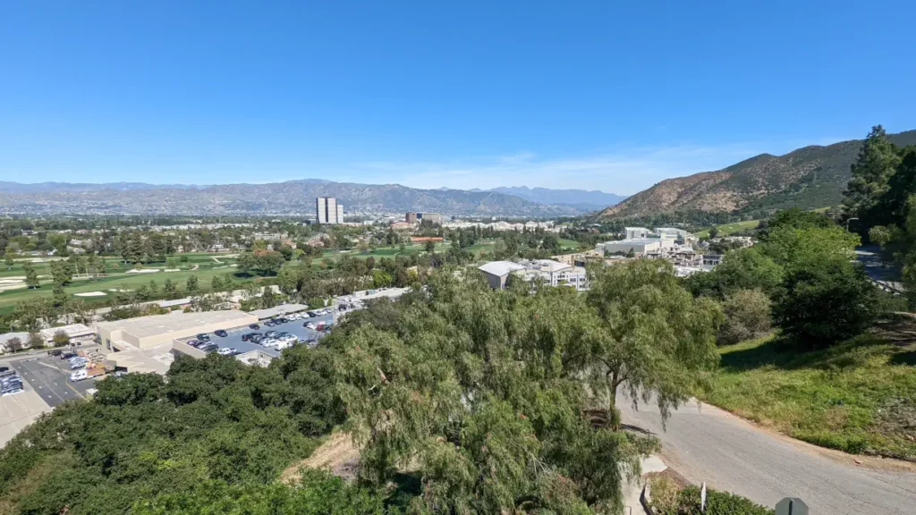 Vue sur Los Angeles depuis le Upper Lot du parc Universal Studio. On y voit beaucoup de verdure et des montagnes.