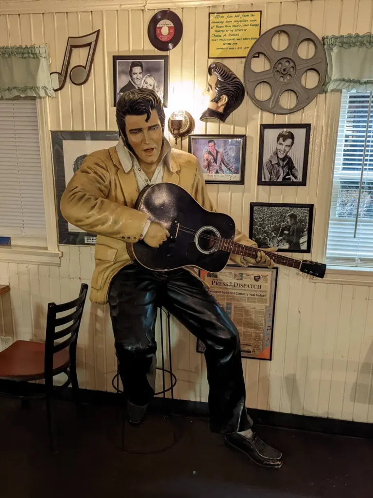 The King, en train de chanter et jouer de la guitare sur un tabouret de la Route 66.