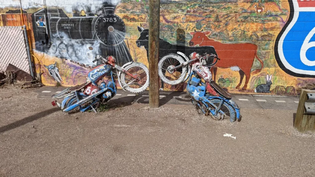 Sculpture de 2 motos aux couleurs des USA, appuyées contre un poteau de la Route 66.